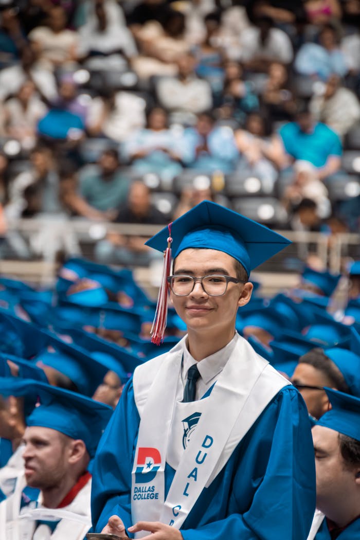 A graduate in blue attire celebrates commencement at Dallas College.