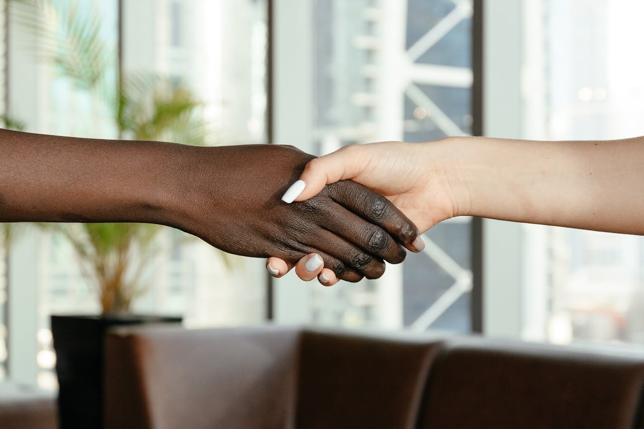 services-03 Crop anonymous diverse women shaking hands together on blurred background of contemporary office